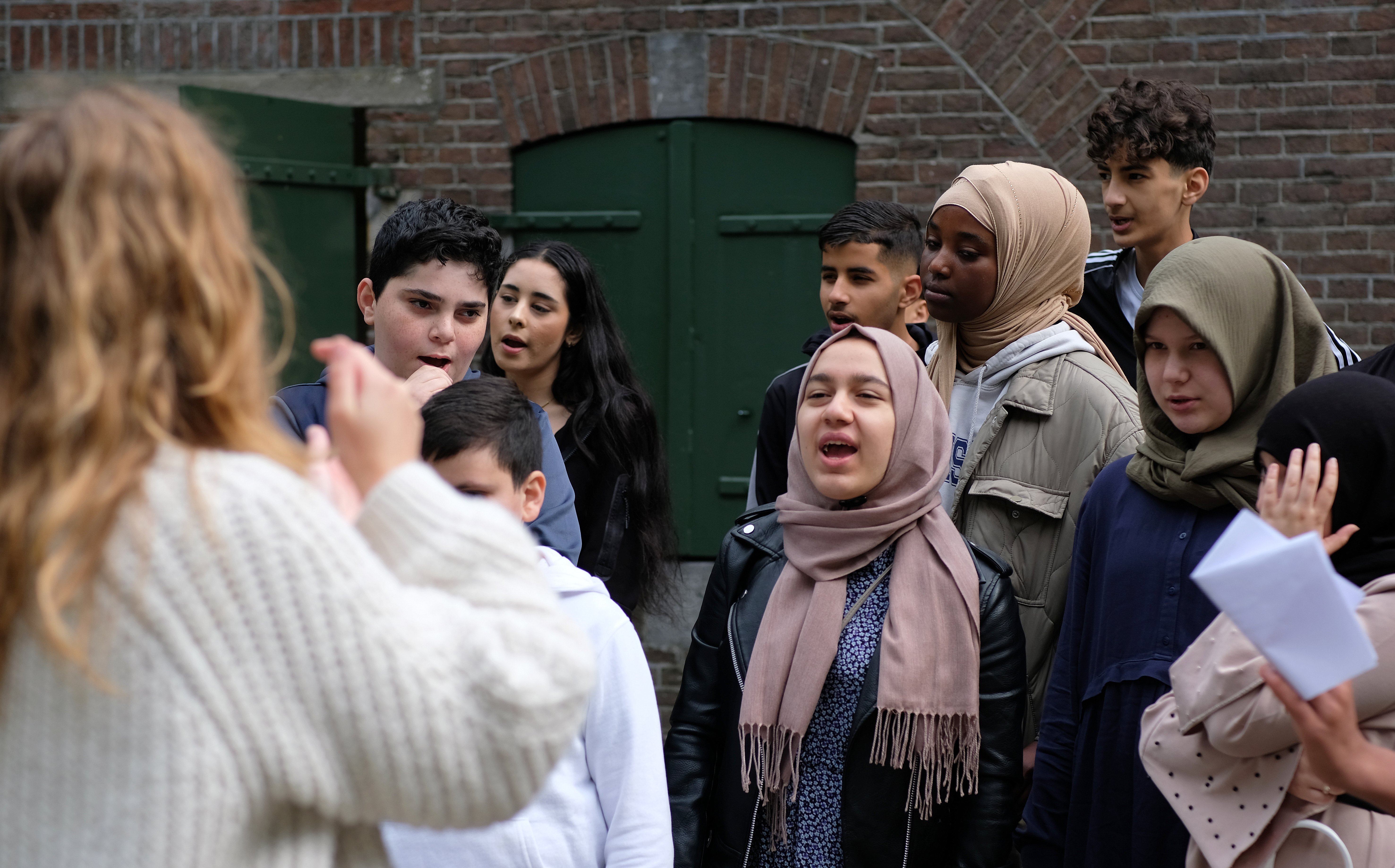 Een groep van ruim 9 leerlingen is aan het zingen bij een Fort