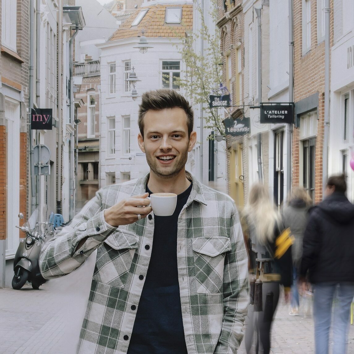 portretfoto Niels van Doormalen in winkelstraat met kop koffie in hand
